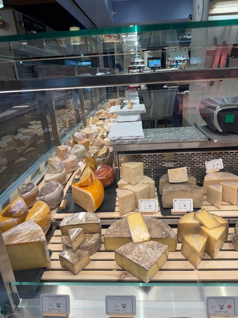 Cheeses displayed at a counter inside Les Halles de Lyon