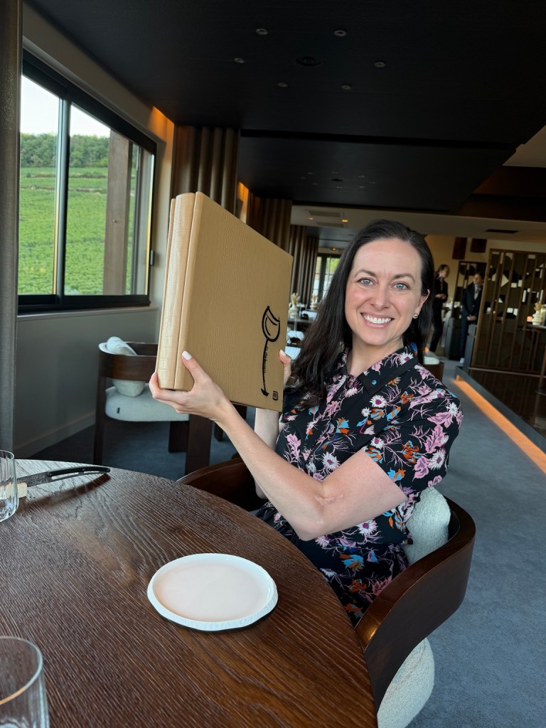 Bridget holding a large wine list at Le Charlemagne