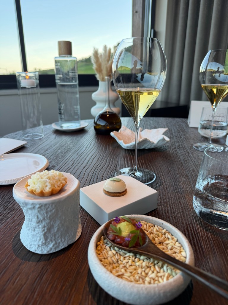 Small dishes and wine beside a vineyard-facing window