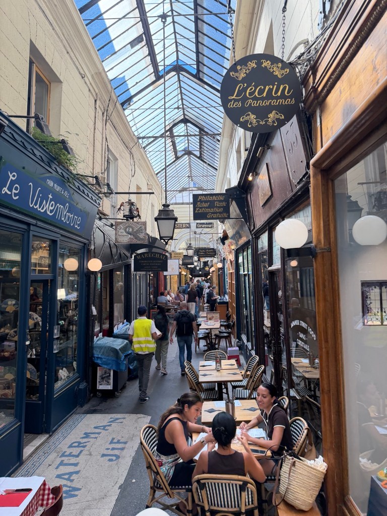Shops and dining tables beneath a glass roof in Paris